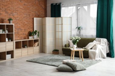 Katlanır ekran, kanepe ve pencereli şık bir oturma odası.