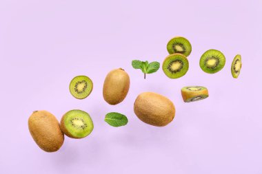 Taze kivi ve nane yaprakları leylak arka planda uçuşuyor.