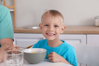 Mutlu küçük oğlu ve babası kahvaltıda mısır gevreği ve süt yiyorlar.