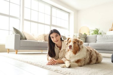 Avustralya çoban köpeği olan genç bir kadın evde yerde yatıyor.
