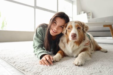 Avustralya çoban köpeği olan genç bir kadın evde halıda yatıyor.