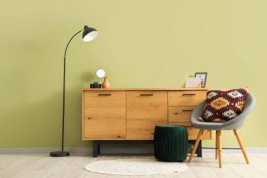 Yer lambası, çekmece sandığı ve şık bir odada yeşil duvarın yanında sandalye.