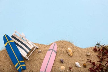 Güverte sandalyesi, sörf tahtaları, kumlar ve deniz kabukları mavi arka planda. Yaz konsepti