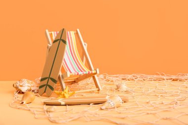 Güverte sandalyesi, sörf tahtaları ve turuncu arka planda deniz kabukları. Yaz konsepti