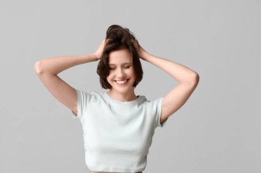 Beautiful young happy woman with bob hairstyle on grey background clipart