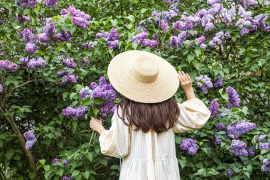 Bahar günü, çiçek açan mor leylak ağacının yanında güzel bir kadın.