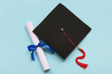Mavi kurdeleli diploma ve açık mavi arka planda mezuniyet şapkası.