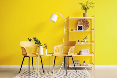 Oturma odasının içinde koltuklar, masa ve yapay bitkiler.