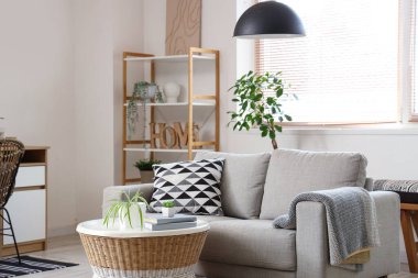 Gri kanepesi, sehpası, işyeri ve raf ünitesi olan şık bir oturma odası.