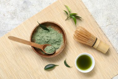 Beyaz zemin üzerinde chasen olan bir kase kibrit tozu ve çay.