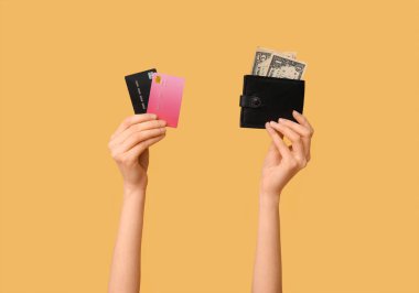 Female hands with credit cards and wallet on yellow background