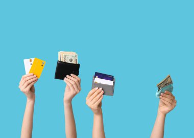 Mavi arka planda kredi kartları ve cüzdanı olan kadın eller.