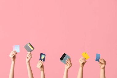 Female hands with credit cards on pink background