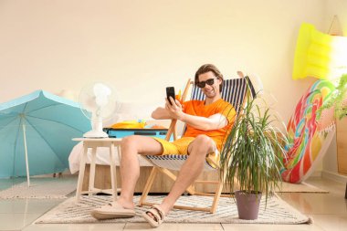 Kokteylli erkek turist tatilde iskemlede selfie çekiyor.