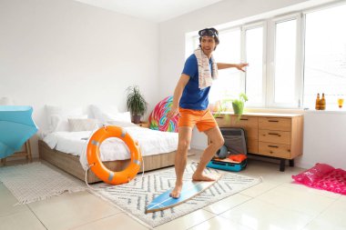 Şnorkel maskeli ve sörf tahtası olan erkek turist tatilde yatak odasında.