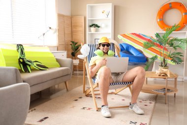 Erkek turist tatilde dizüstü bilgisayar kullanıyor.