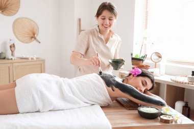 Kaplıcada çamur tedavisi gören genç bir kadın.