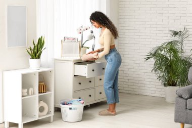 Güzel, genç, mutlu, Afro-Amerikan bir kadın evde temiz giysiler giyiyor.