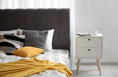 Yatak odasındaki rahat yatağın yanında dergi ve bir fincan kahveyle komodinin yanında.