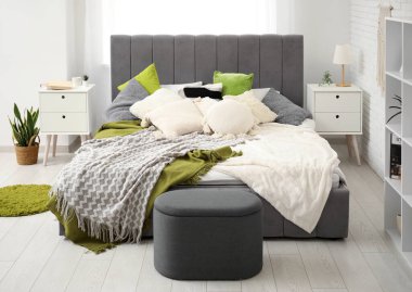 Yataklı, komodinli, puf ve raf üniteli modern yatak odası.