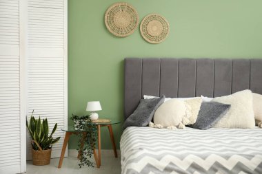 Yatak odasındaki rahat yatağın yanında lamba olan cam komodin.