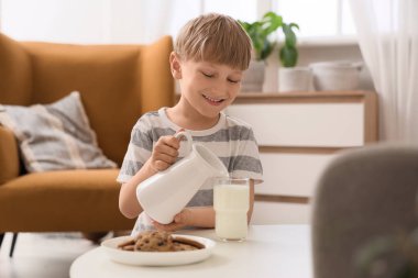 Evdeki bardağa süt döken tatlı küçük çocuk.