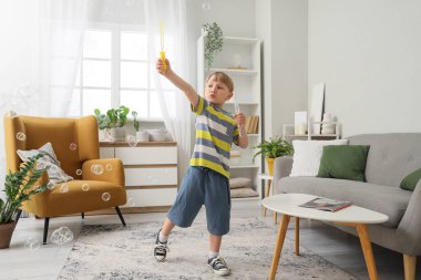 Evde sabun köpüğü üfleyen sevimli küçük çocuk.