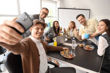 Ofiste öğle yemeğinde selfie çeken bir grup iş adamı.