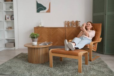 Güzel kızıl saçlı kadın, sevimli bir fareyle evdeki koltukta uzanıyor.