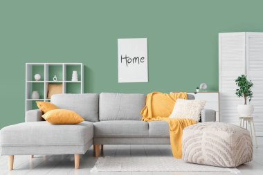 İçinde rahat bir kanepe, resim, puf ve raf ünitesi olan güzel bir oturma odası.