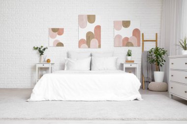 Rahat yataklı, komodinli, çekmeceli ve beyaz tuğlalı duvarlı güzel yatak odasının içi.