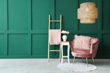 Pembe koltuk ve yeşil duvarın yanındaki çiçekli kahve masası.