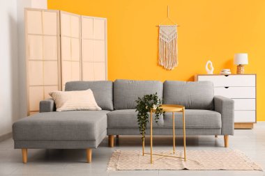 Oturma odasında bitki bulunan rahat bir kanepe ve kahve masası.