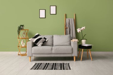 Oturma odasında rahat bir kanepe, orkide ve açık bir kitapla kahve masası.