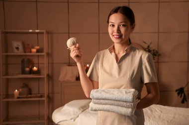 Koyu kaplıcada havlu ve bitki torbasıyla Asyalı kadın masaj terapisti.