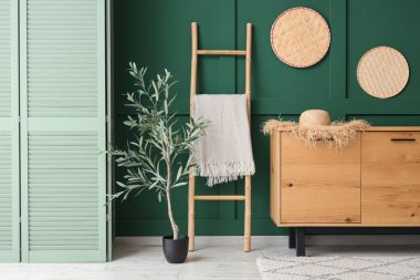 Oturma odasının içinde merdiven, çekmece ve zeytin ağacı var.