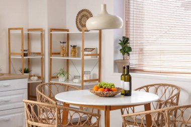 Yemek masası, raf ünitesi, sandalye ve lamba olan şık bir mutfak.