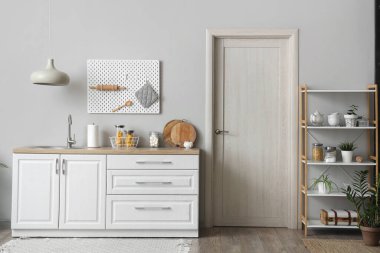 Beyaz tezgahları, kapısı, raf ünitesi ve lambası olan güzel bir mutfak.