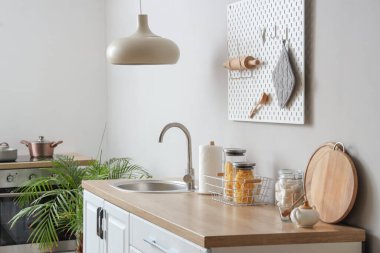 Beyaz tezgahları, lavabosu ve lambası olan güzel bir mutfak.