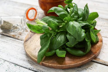 Beyaz ahşap arka planda taze yeşil fesleğen yapraklı tabak.