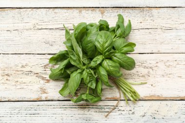 Beyaz ahşap arka planda taze yeşil fesleğen yaprakları