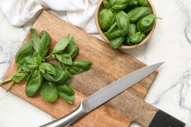 Tahta kase ve beyaz arka planda taze yeşil fesleğen yaprakları.