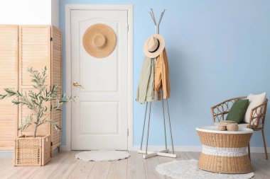 Rahat koltuğu, giysi rafı, kapısı ve zeytin ağacı olan güzel bir oturma odası.