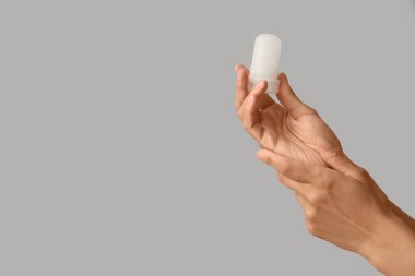 Gri arka planda deodorantı olan kadın elleri