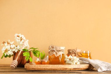 Bir kâse bal ve akasya çiçekli ahşap masa.