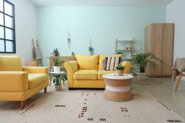 Şık, modern oturma odasının içinde sarı kanepeler ve bitkiler var.