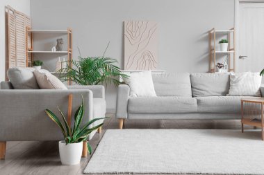 Gri kanepeleri ve çiçekleri olan modern bir oturma odası.