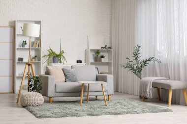 Katlanır ekran, gri kanepe, raf ünitesi ve sehpası olan şık bir oturma odası.