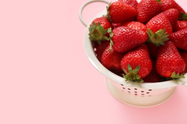 Pembe arka planda tatlı taze çilekli Colander.