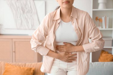 Evde adet sancısı çeken genç bir kadın, yakın çekim.